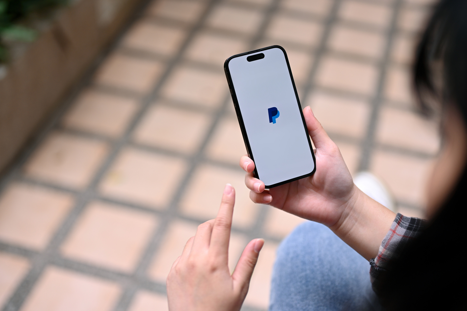 an Asian woman using PayPal application on her smartphone. iPhon