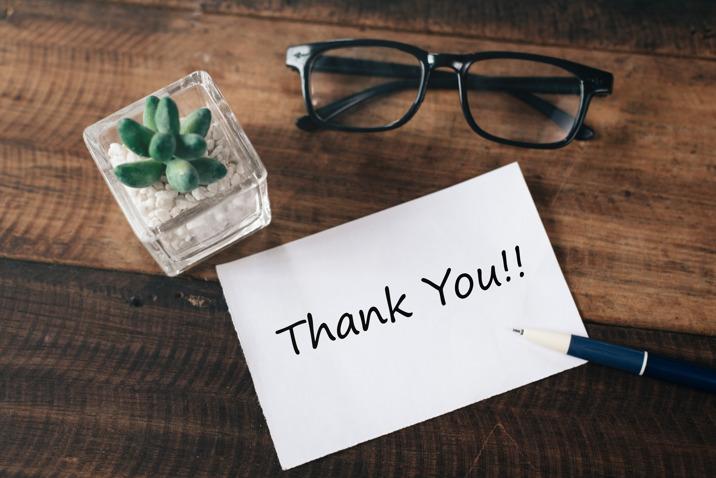 High Angle View Of Thank You Text On Paper With Plant And Eyeglasses On Wooden Table